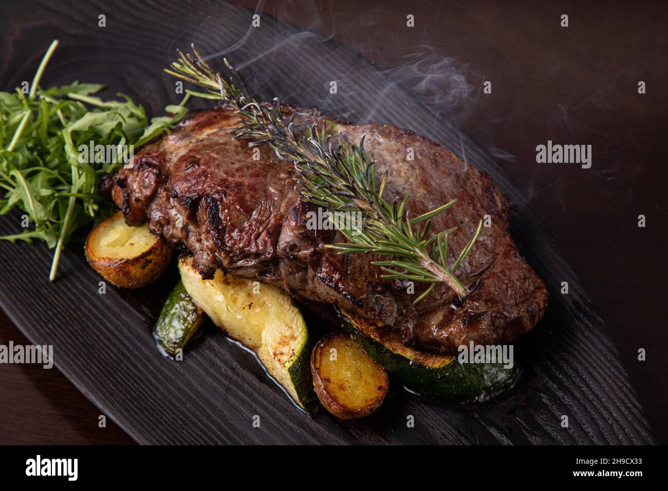Bistecca di striploin alla griglia su piatto nero. bistecca con patate fritte e verdure Foto Stock