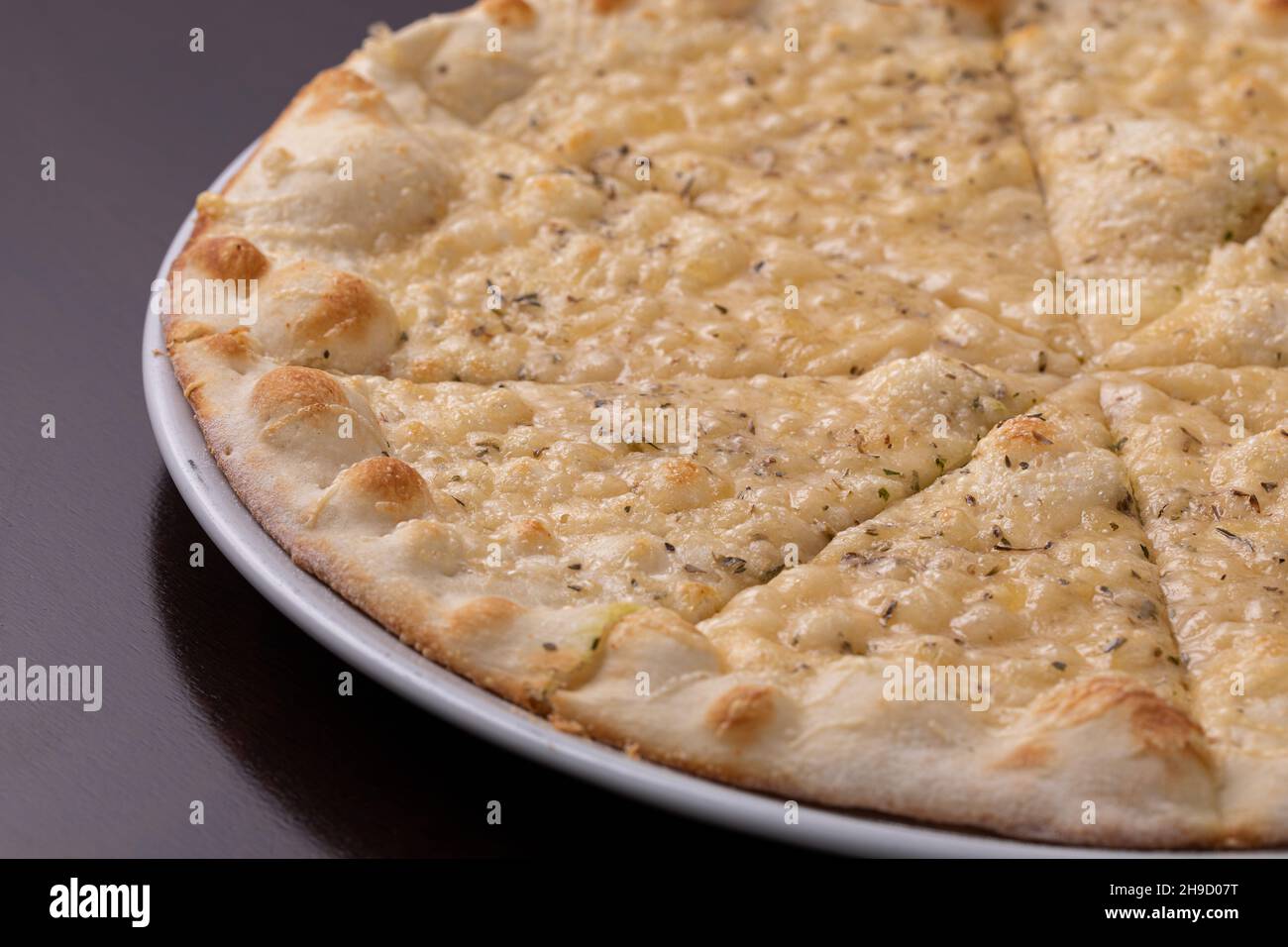 Focaccia con formaggio su piatto bianco su tavola di legno scuro Foto Stock