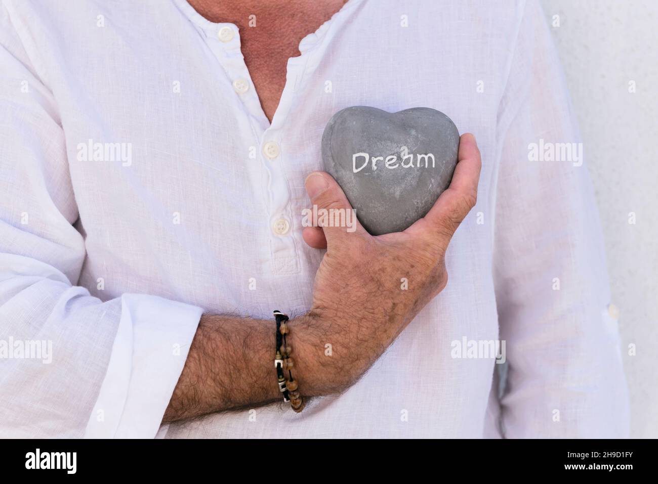 Uomo che tiene la pietra a forma di hart con la parola ‘Deam’ Foto Stock