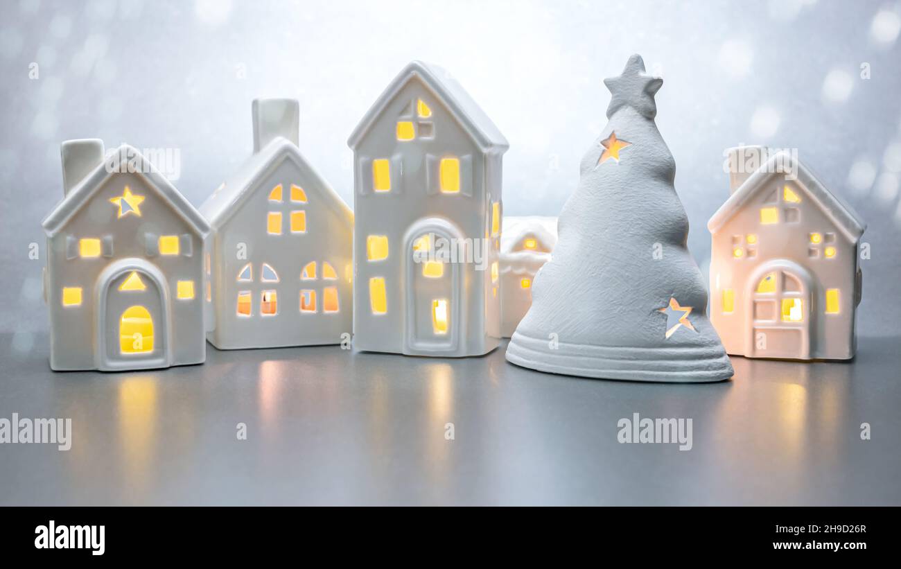case bianche giocattolo illuminate con abete su sfondo grigio. biglietto di auguri di natale. Foto Stock