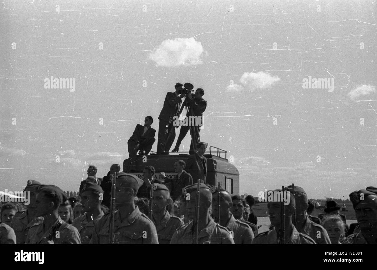 Warszawa, 1947-09-07. Obchody Œwiêta Lottictha. Uroczystoœæ przekazania sztandaru Samodzielnemu Pu³kowi Lotniczemu na terenie lotniska wojskowego Okêcie. NZ. Operatorzy Polskiej Kroniki Filmowej, filmuj¹ z dachu samochodu przebieg uroczystoœci. po/ms PAP Varsavia, 7 settembre 1947. Cerimonie che segnano il giorno dell'Aviazione. La cerimonia di trasferimento della bandiera al Reggimento aereo indipendente all'aeroporto militare di Okecie. Nella foto: Cameramen del newsreel polacco che riprende il corso della cerimonia dal tetto di una macchina. po/ms PAP Foto Stock