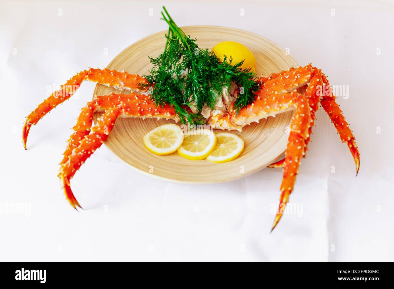 Red king crab su una piastra con limone e aneto. Sfondo bianco Foto Stock