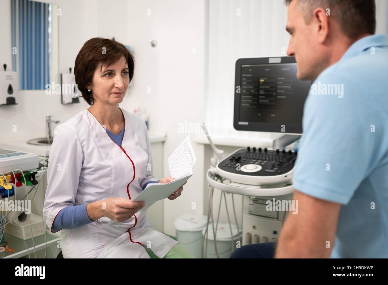 Il cardiologo medico presso l'ufficio di diagnostica ecografica con il paziente esamina le prove mediche durante un controllo di salute in una clinica moderna Foto Stock