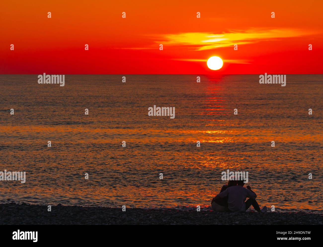 Coppia innamorata sulla riva del mare sullo sfondo del tramonto del sole Foto Stock
