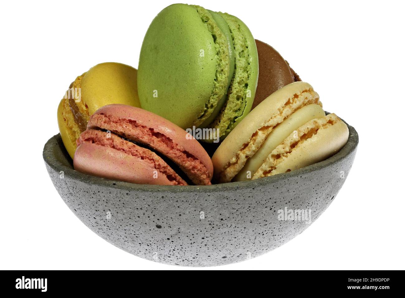 macaron colorati in una ciotola di cemento isolato su sfondo bianco Foto Stock