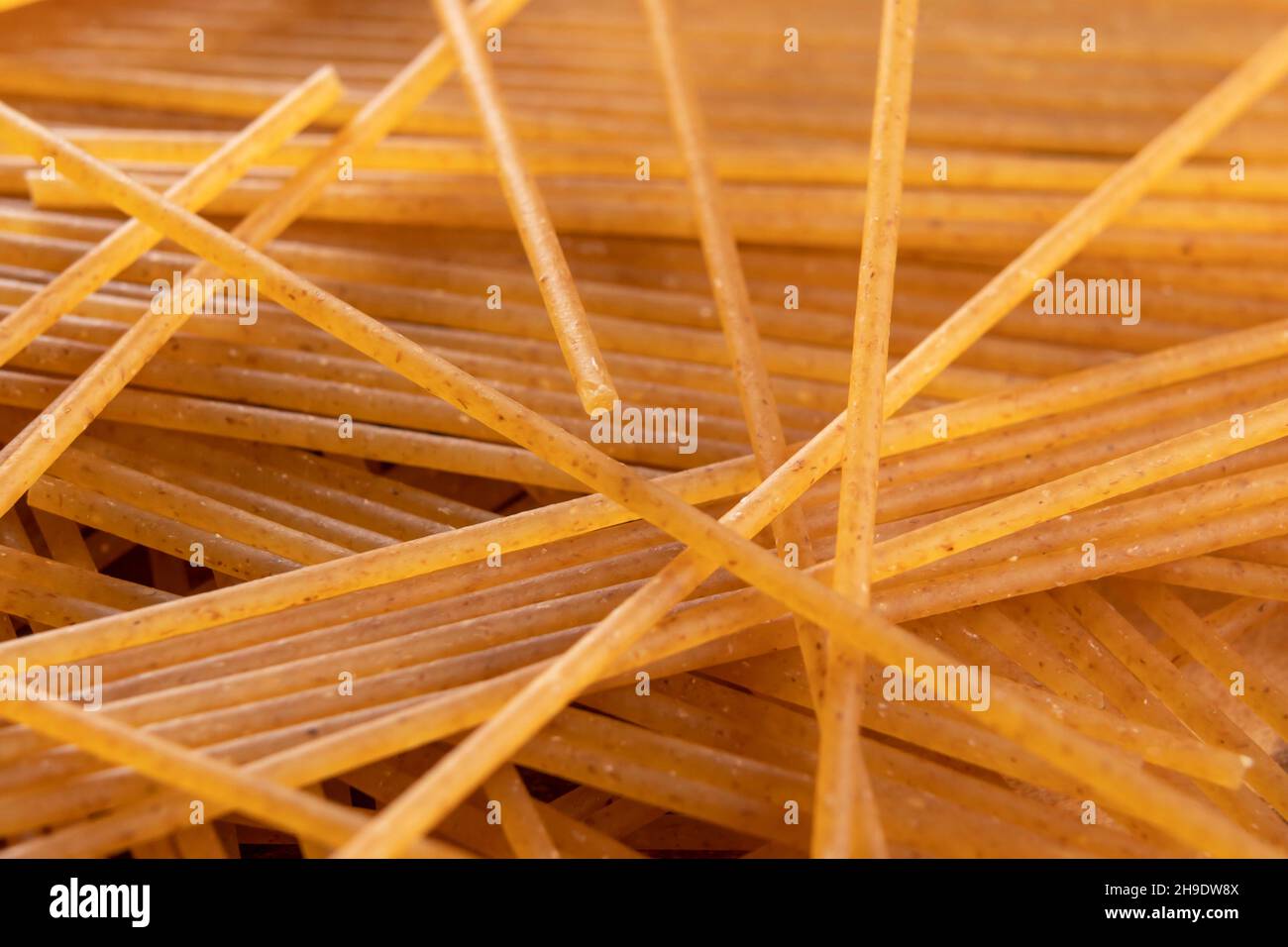 Mazzo di spaghetti crudi di frumento intero. Macro. Cibo integrale secco. Pasta organica marrone Foto Stock