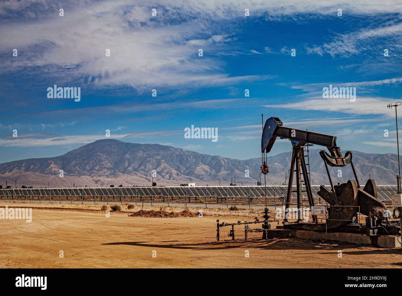 Pumpjack Lone situato nel mezzo di un grande impianto solare al di fuori di Bakersfield, Kern Coutny, California, Stati Uniti Foto Stock