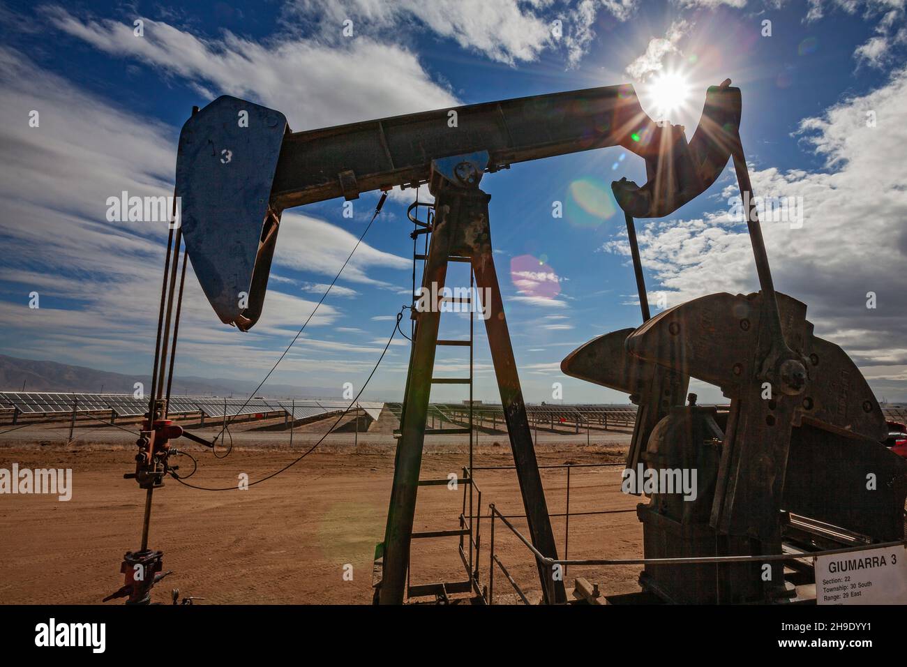 Pumpjack Lone situato nel mezzo di un grande impianto solare al di fuori di Bakersfield, Kern Coutny, California, Stati Uniti Foto Stock