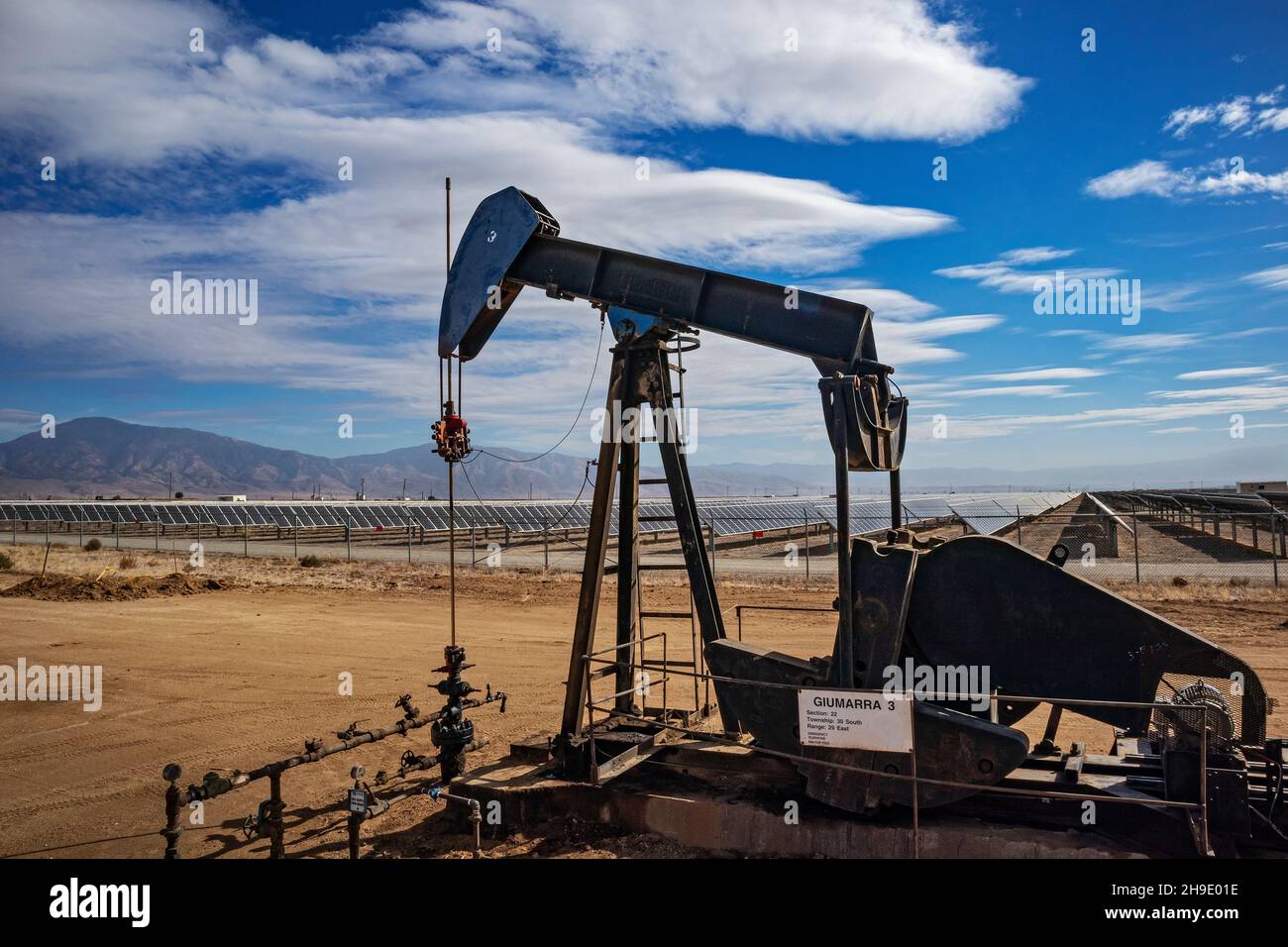 Pumpjack Lone situato nel mezzo di un grande impianto solare al di fuori di Bakersfield, Kern Coutny, California, Stati Uniti Foto Stock