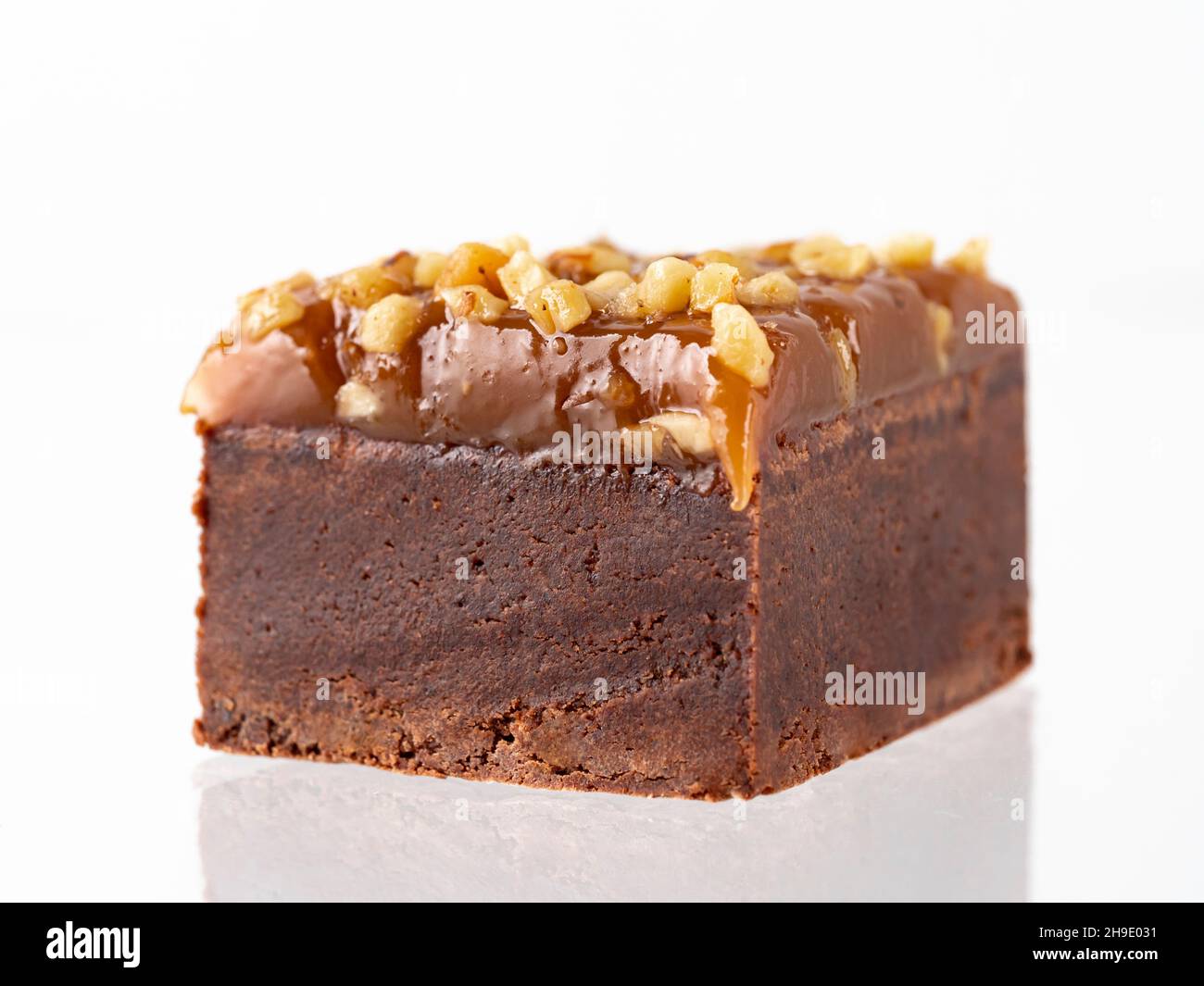 Torta al cioccolato brownie isolata su bianco. Bite size brownie al cioccolato marrone umido con guarnizione di caramello e arachidi, isolato su sfondo bianco con percorso di taglio. Foto Stock