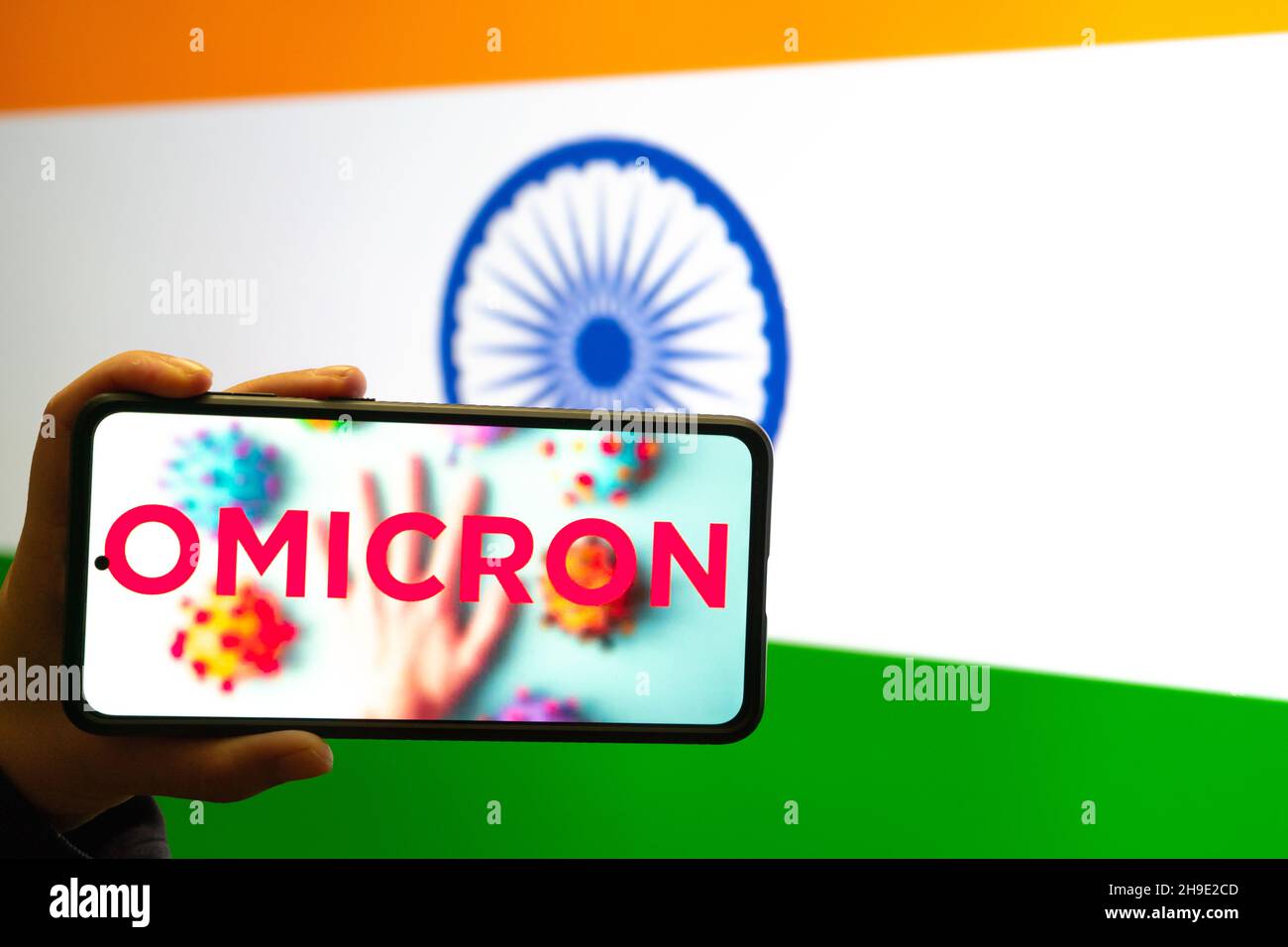 Telefono cellulare portatile con omicron COVID 19 variante ceppo di fronte alla bandiera dell'India mostrando notizie app notifica Foto Stock