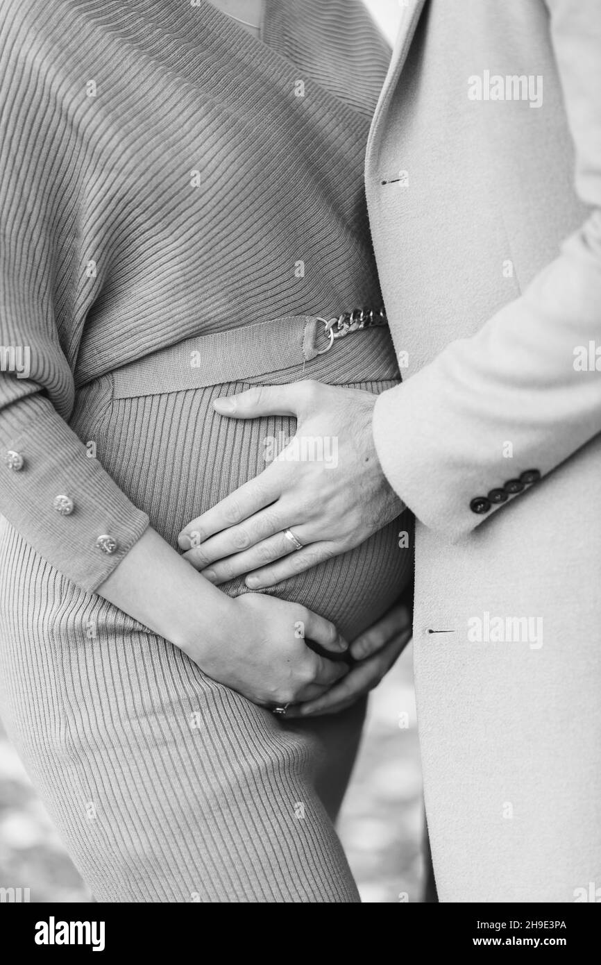 Primo piano in scala di grigi di una donna incinta con un uomo che abbraccia Foto Stock