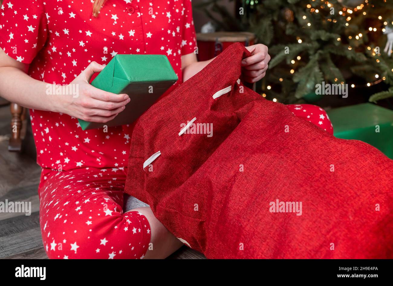 Mani primo piano mettere la scatola regalo verde in borsa rosso di Natale. Il concetto di preparazione di Natale. Foto Stock