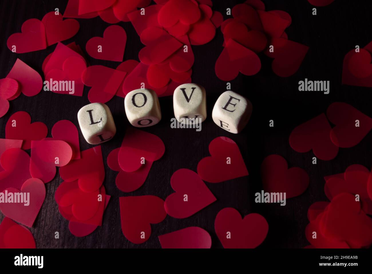 La parola AMORE da cubi di legno su legno scuro. San Valentino sfondo Foto Stock