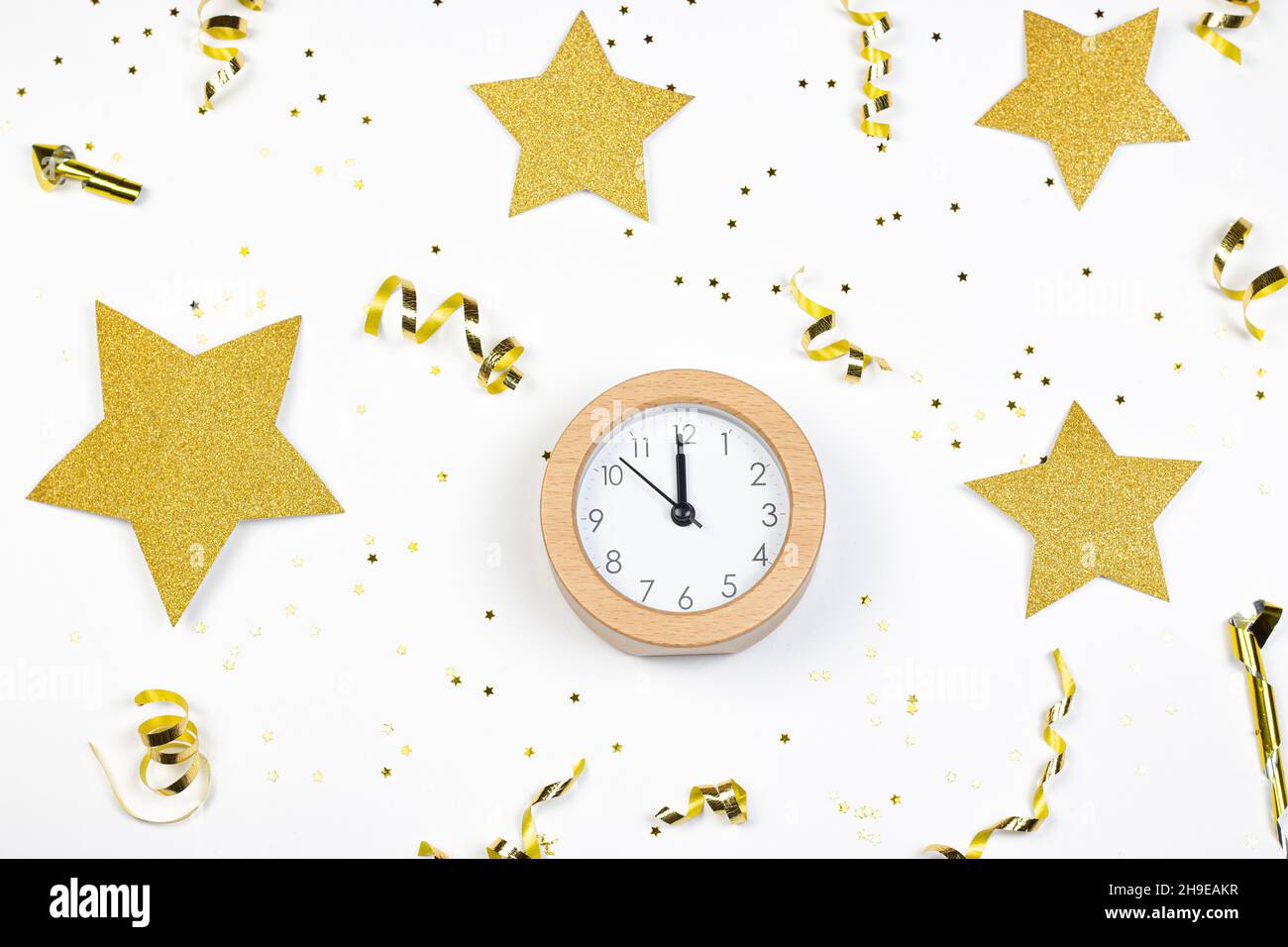 Concetto del tempo del partito. Orologio, stelle glitter e confetti dorati su sfondo bianco. Disposizione piatta. Foto Stock
