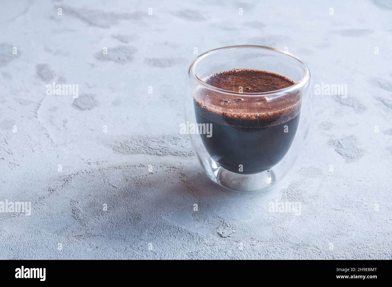 Caffè caldo in vetro a doppia parete su sfondo grigio in cemento Foto Stock