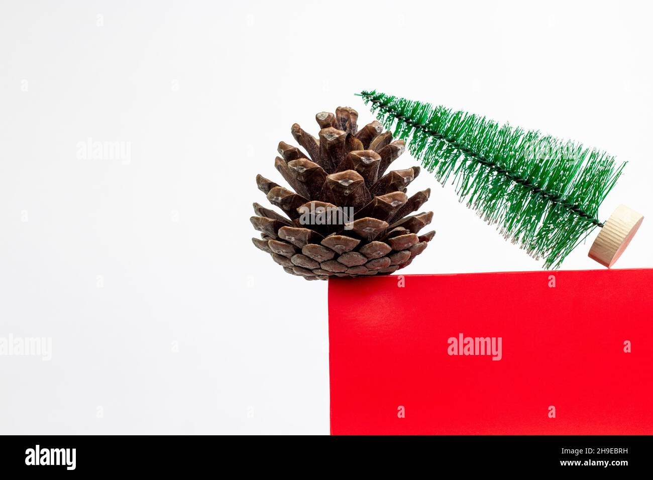 Fuoco cono e piccolo albero di Natale su un podio a forma di cubo rosso. Composizione minima per le vacanze di Natale con spazio per la copia Foto Stock
