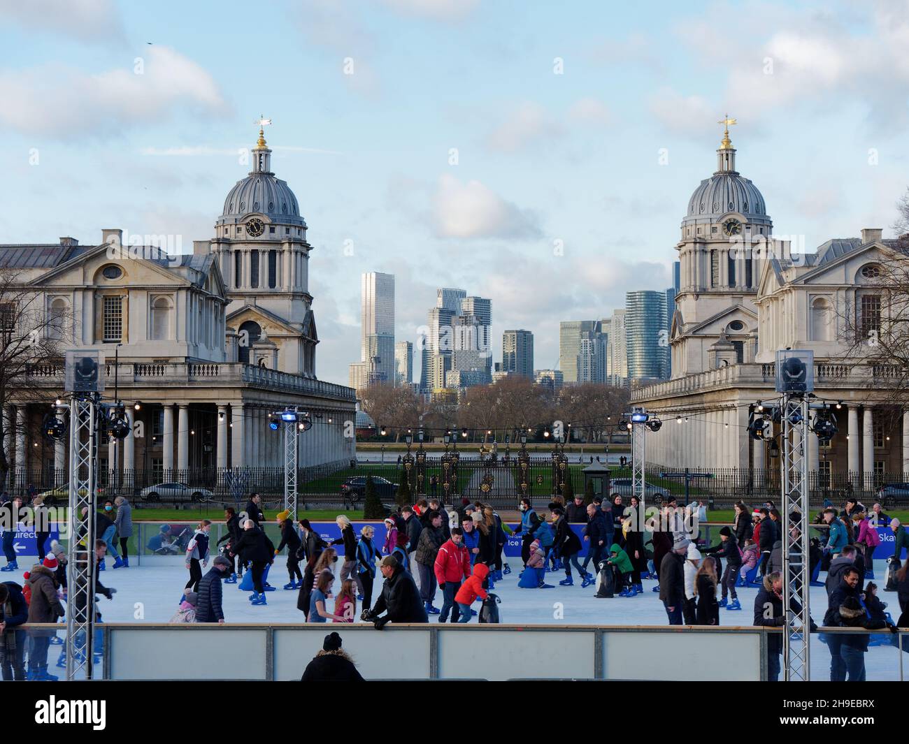 Londra, Greater London, Inghilterra, dicembre 04 2021: Persone che pattinano sulla pista di pattinaggio a Greenwich a Natale con gli edifici universitari alle spalle Foto Stock