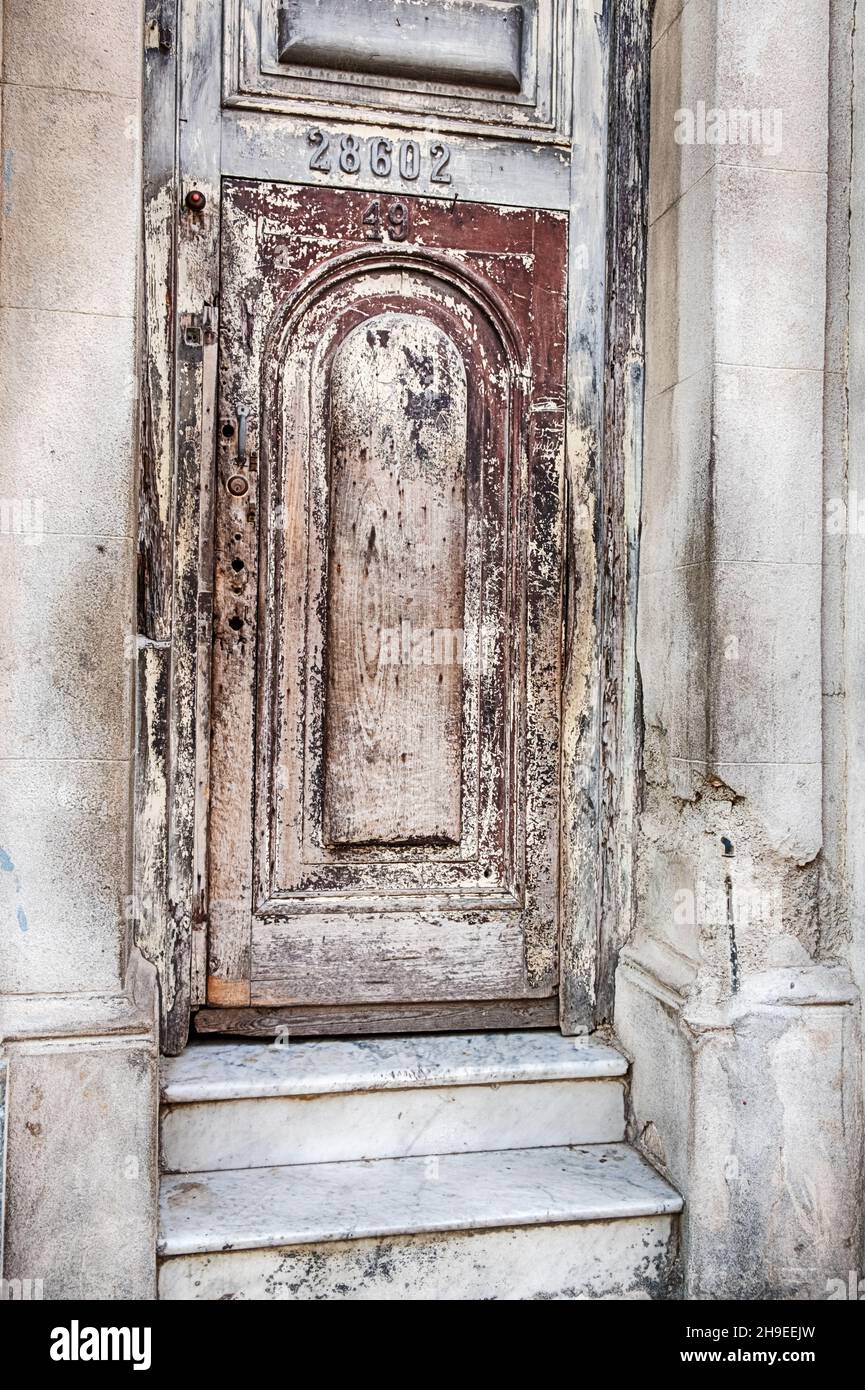 La vernice rossa sbiadita su una vecchia porta di legno sta gradualmente decadendo nella città di Matanzas a Cuba. Foto Stock