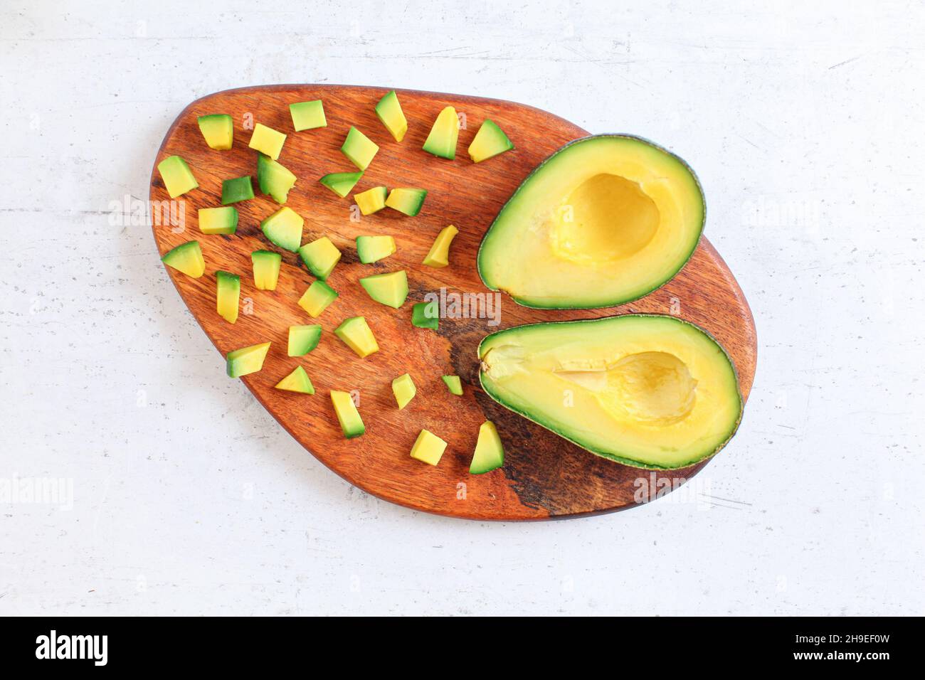 Polpa di avocado verde giallo tagliata a piccoli pezzi su tagliere di legno, vista dall'alto Foto Stock