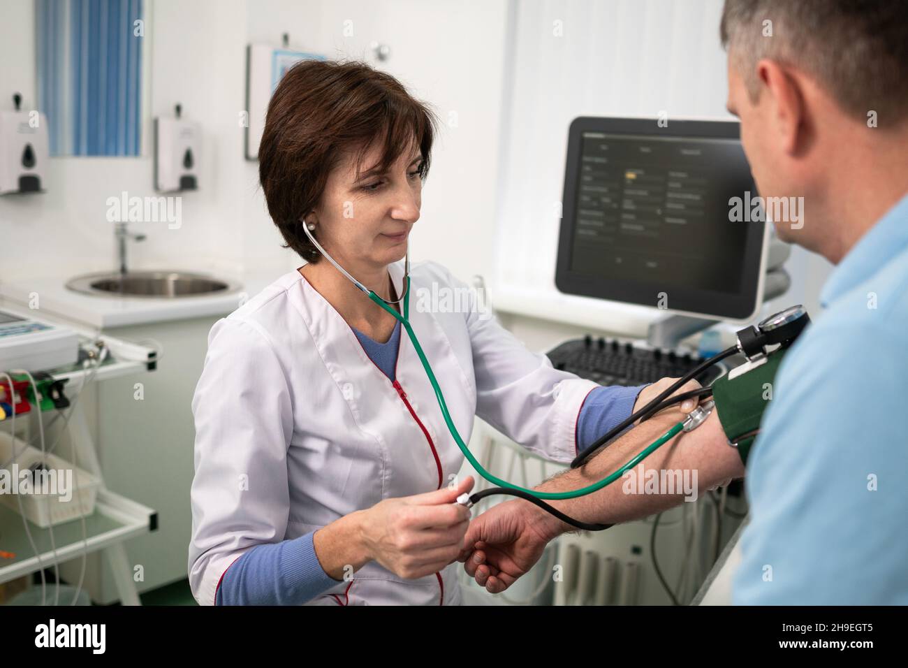 Concetto medico e sanitario. Ipertensione, pressione alta e precursori di ictus in mezza età negli uomini. Controllo medico. Medico femminile in Foto Stock