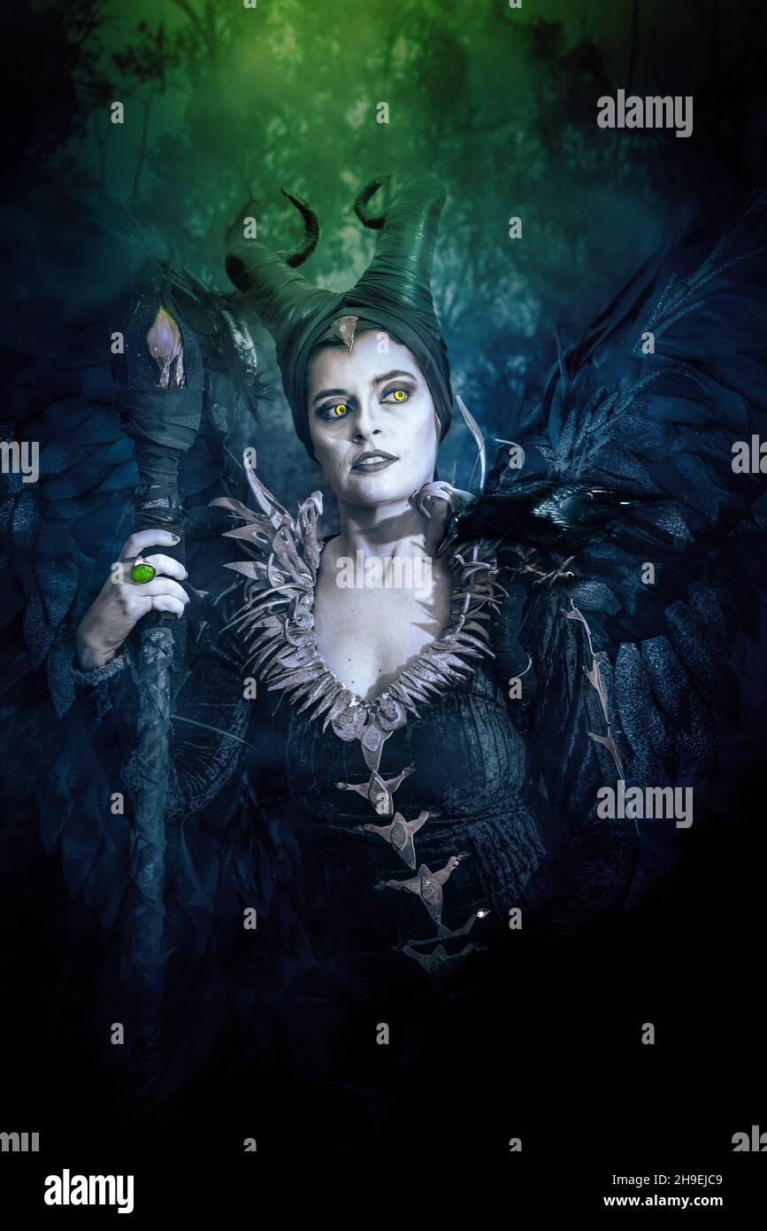 COSPLAY MALEFICO. RITRATTO, CARATTERE SCURO CON CORNA AFFILATE E ALI FORTI. FATA MALVAGIA IN ABITO NERO. VERTICALE, A COLORI. Foto Stock