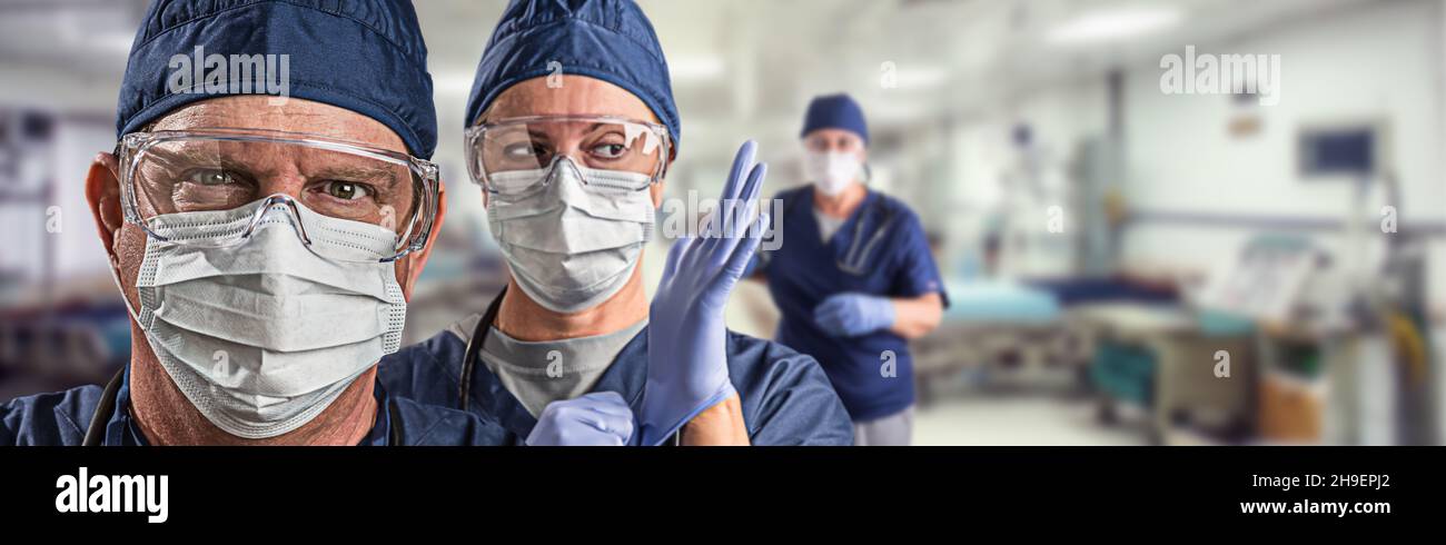 Team di medici o infermieri femminili e maschili che indossano un equiment protettivo personale nella stanza di emergenza ospedaliera. Foto Stock