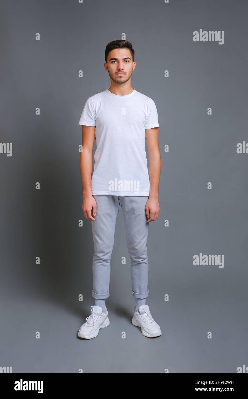 Ritratto a tutta lunghezza di un giovane uomo sicuro in t-shirt bianca Foto Stock