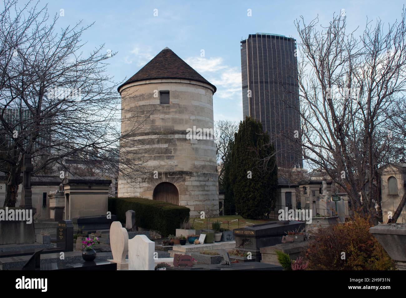 Il mulino a vento senza le sue vele nel cimitero di Montparnasse, con il Tour Montparnasse sullo sfondo Parigi Francia Foto Stock