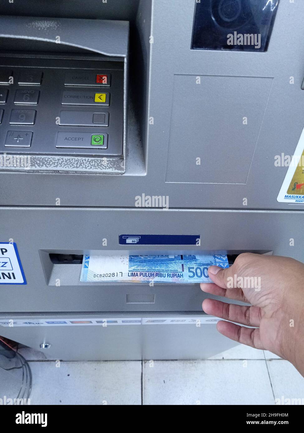 Foto editoriale, Indonesia, Giacarta Est, 02 ottobre 2021, uomo prendere soldi 50000 rupia a ATM BCA Foto Stock