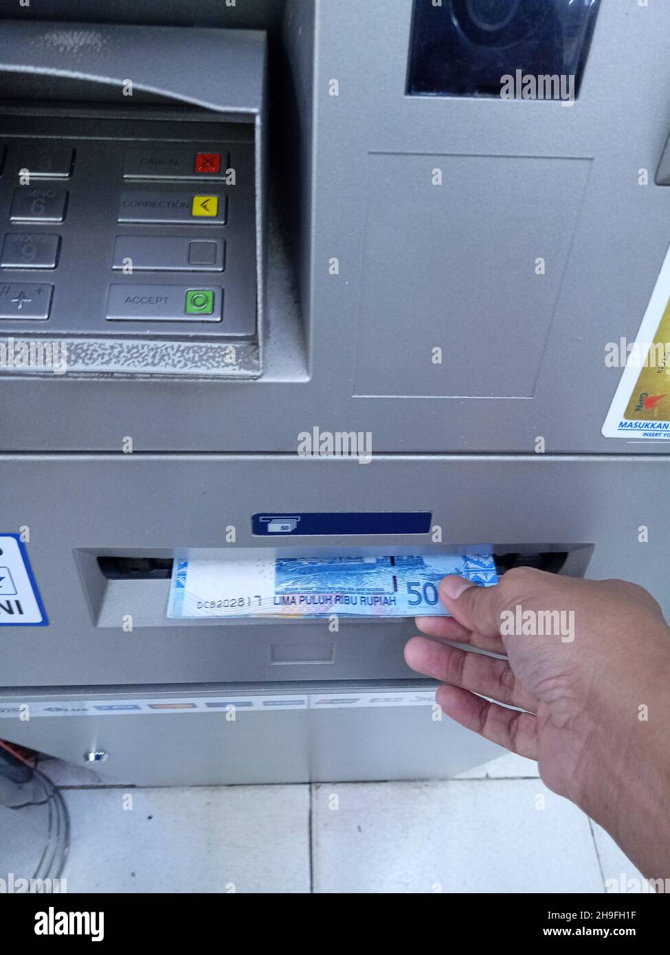 Foto editoriale, Indonesia, Giacarta Est, 02 ottobre 2021, uomo prendere soldi 50000 rupia a ATM BCA Foto Stock