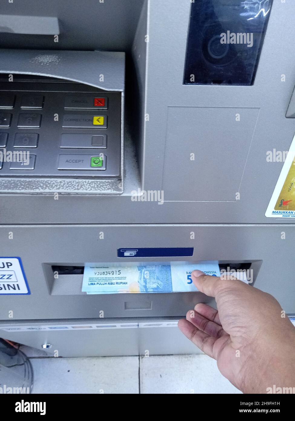 Foto editoriale, Indonesia, Giacarta Est, 02 ottobre 2021, uomo prendere soldi 50000 rupia a ATM BCA Foto Stock