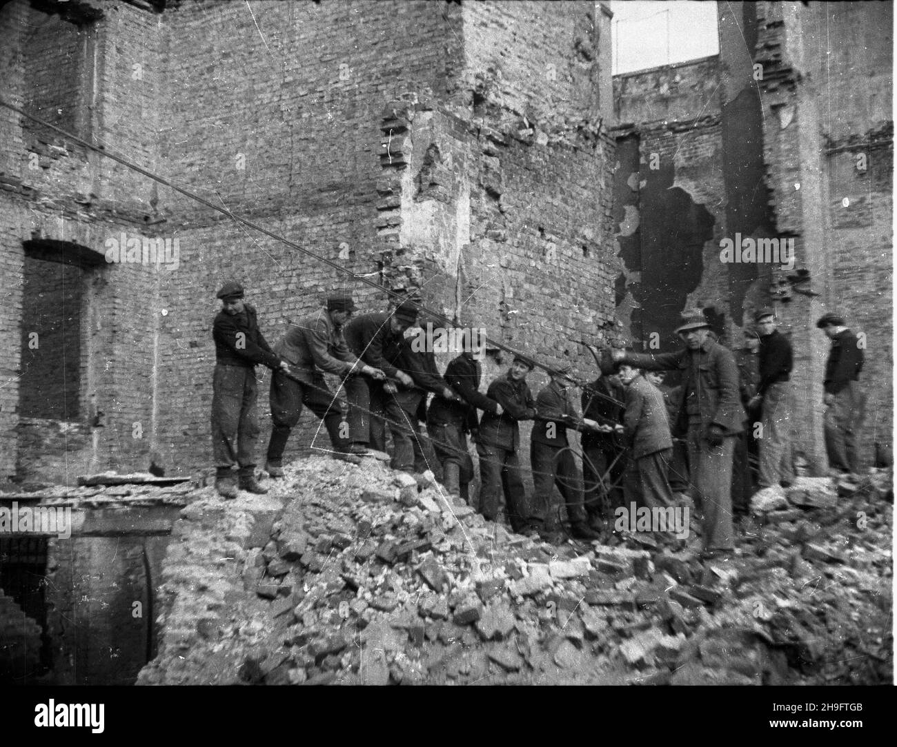 Warszawa, 1948-03. Uprz¹tanie terenu pod budowê Zak³adów Graficznych Dom S³owa Polskiego w pobli¿u placu Kazimierza Wielkiego. Robotnicy w trakcie rozbiórki zburzonego podczas II wojny œwiatowej domu. uu PAP Dok³adny dzieñ wydarzenia nieustalony. Varsavia, marzo 1948. Rimozione delle macerie presso il cantiere della stamperia Dom Slowa Polskiego vicino a Piazza Kazimierza Wielkiego. Nella foto: Demolizione di un edificio danneggiato dalla guerra. uu PAP Foto Stock