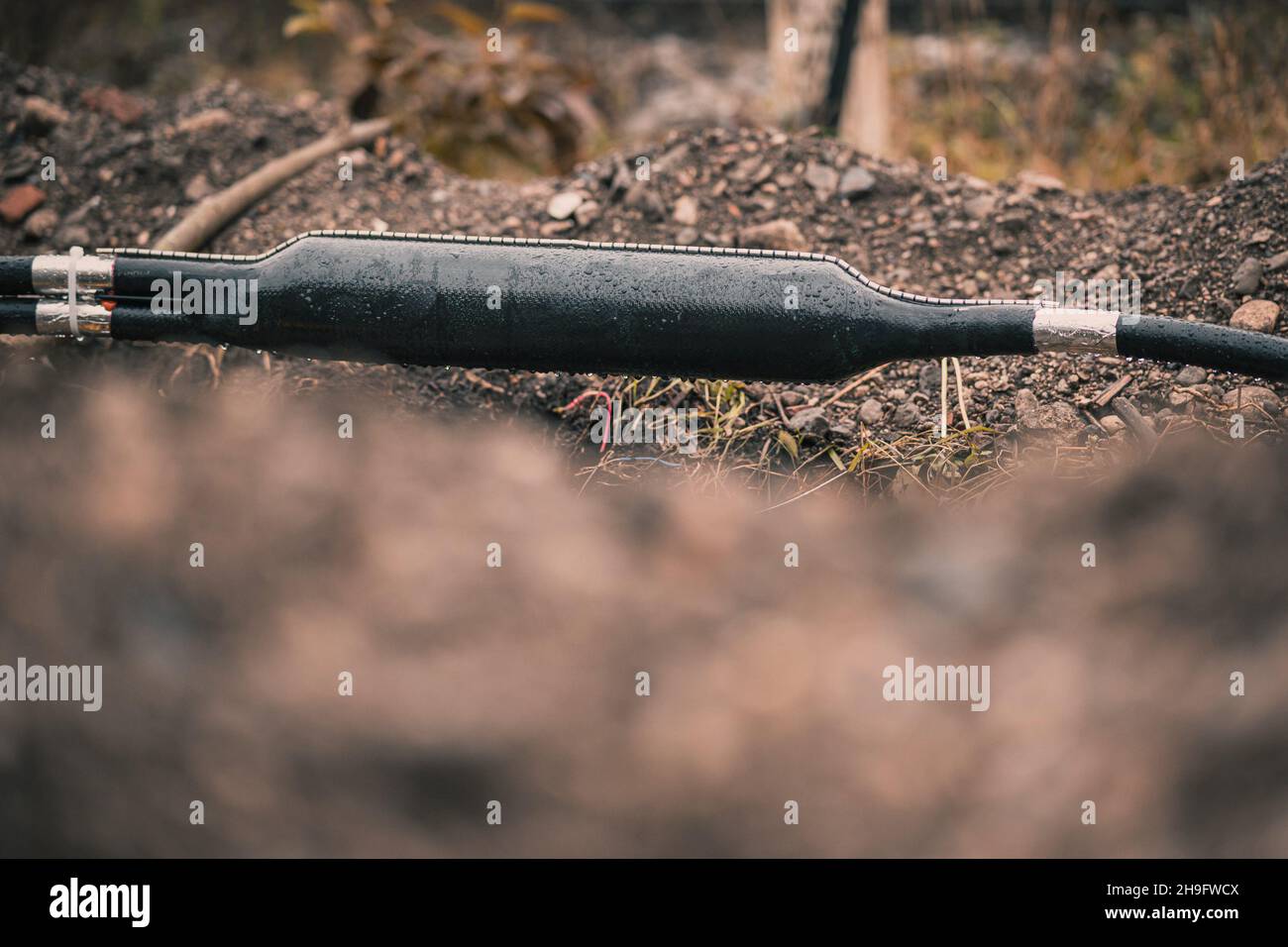 Collegamento di cavi ottici industriali, suddivisione a Y di un cavo, schermato in un contenitore in plastica visto scavato da terra o trincea in un cantiere. Foto Stock