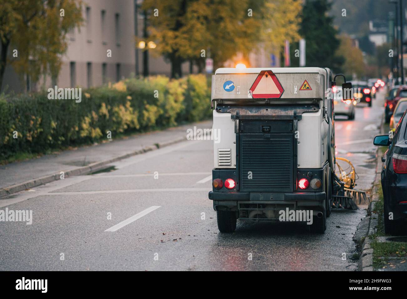 Veicolo più pulito che pervina le strade della città. Macchina spazzatrice stradale che fa problemi nel traffico mattutino. Foto Stock