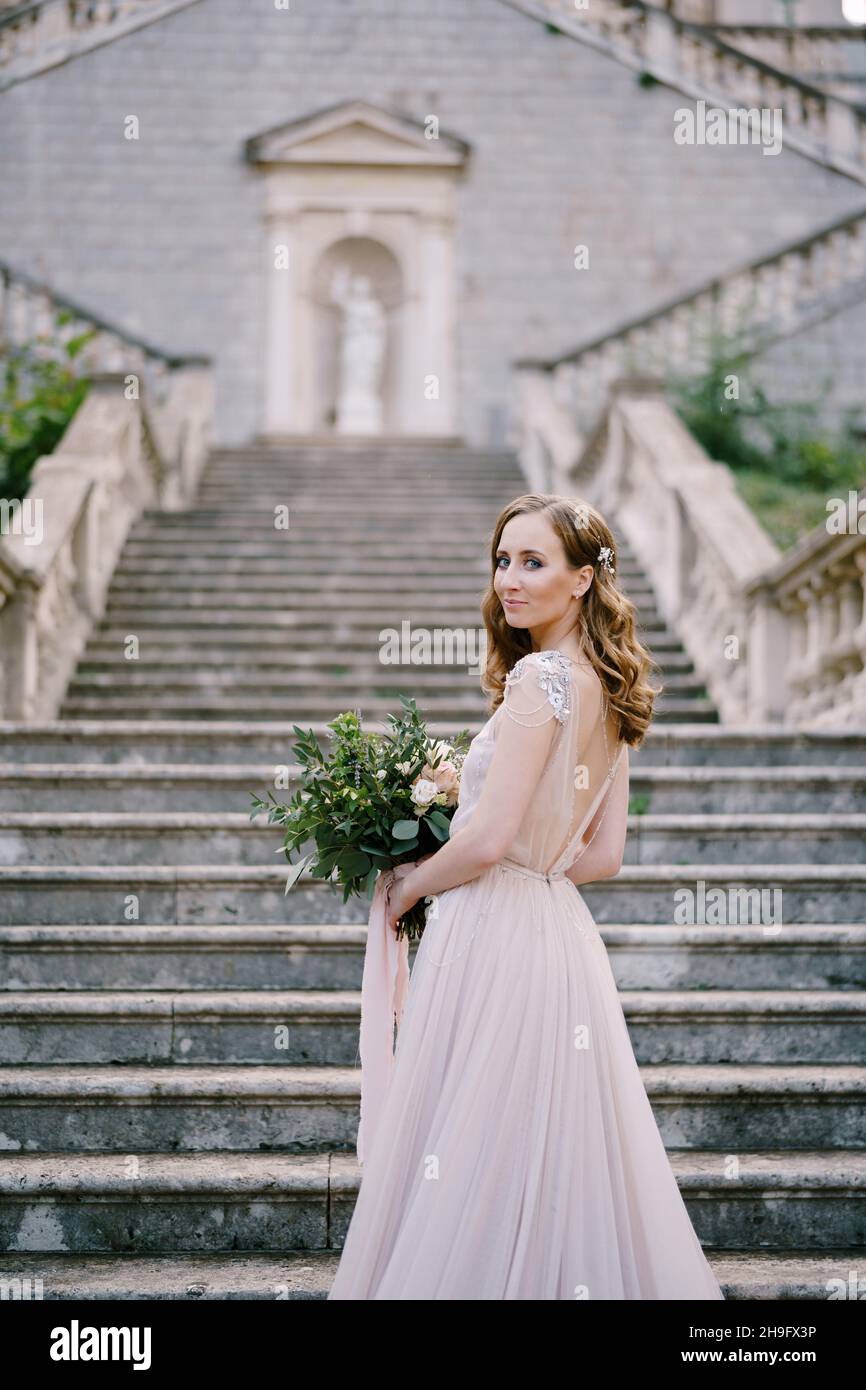 La sposa si erge a metà sui gradini di pietra vicino al vecchio edificio Foto Stock