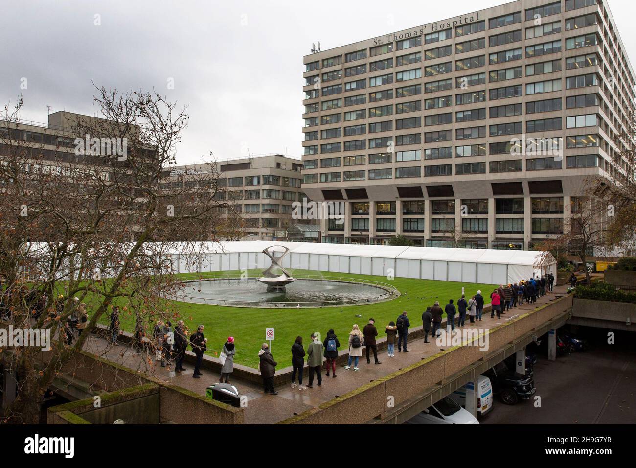 Le persone si accodano al di fuori del St Thomas Hospital, South London, per ricevere il booster jab di Covid mentre la variante Omnicron prende piede nel Regno Unito. Foto Stock