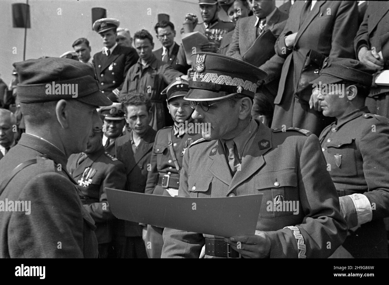 Gdynia, 1948-06-08. Uroczystoœæ ods³oniêcia tablicy pami¹tkowej ku czci gen. Karola Œwierczewskiego - Waltera, umieszczonej na drobnicowcu M/S Genera³ Walter, zacumowanym w Nowym Porcie. m.in. Komendant g³ówny Milicji Obywatelskiej, wiceminister bezpieczeñstwa publicznego, prezes Zarz¹du G³ównego Zwi¹zku Uczestników Walki Zbrojnej o Niepodleg³oœæ i Demokracjê, genera³ Franciszek JóŸwiak, ps. Witold (C w okularach) wrêcza dyplom cz³onkowi Zwi¹zku D¹browszczaków. Come PAP Gdynia, 8 giugno 1948. La presentazione di una targa al generale Karol Swierczewski alias Walter sul bordo di M/S Gener Foto Stock