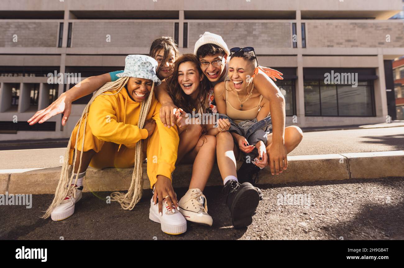 Ricordi felici con gli amici. Gruppo di amici di generazione z ridere allegro mentre si aggrappano insieme all'aperto in città. Buon venerdì Foto Stock