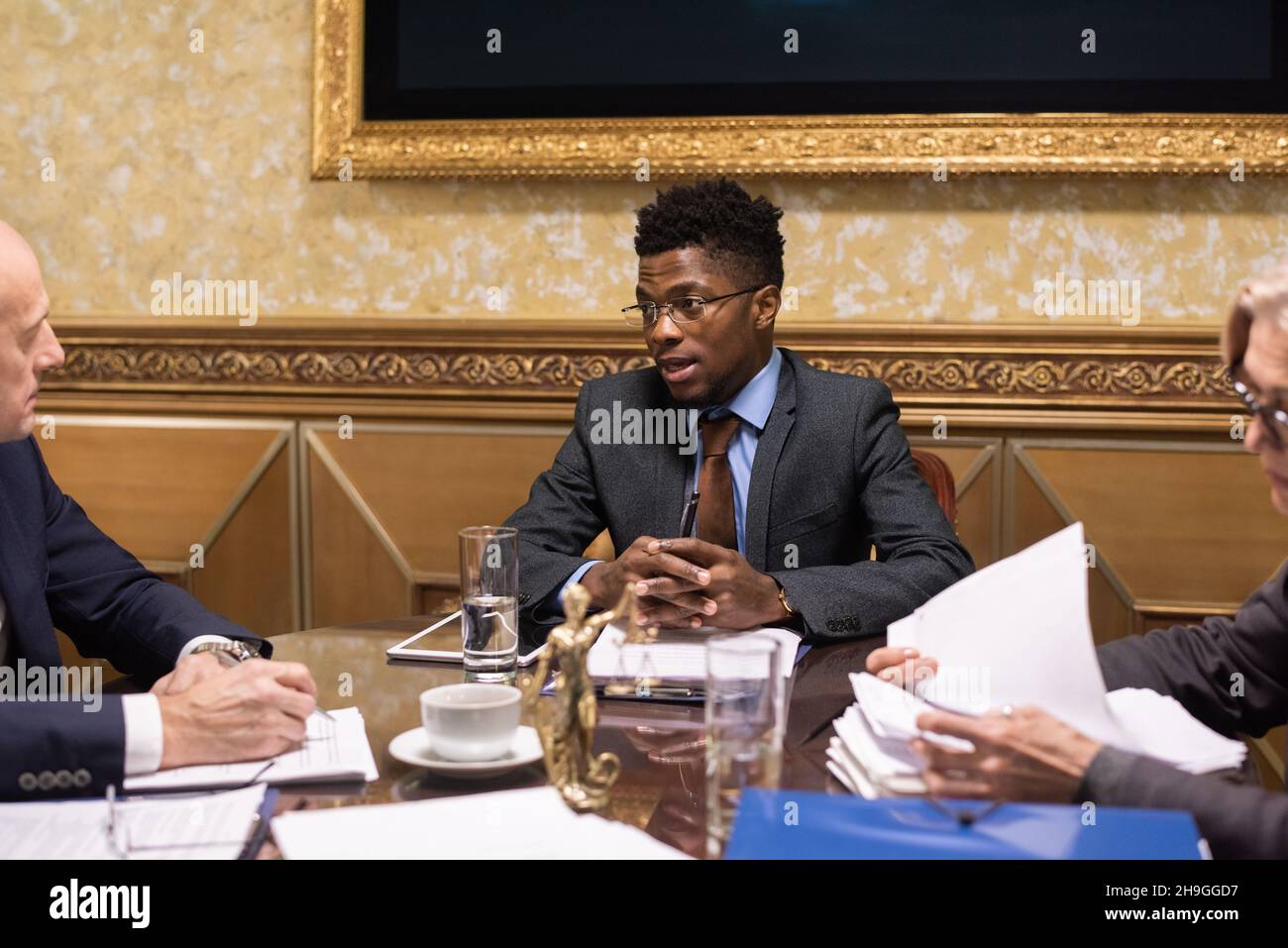 Giovane avvocato fiducioso di etnia africana che parla con un collega maschio maturo sui termini di contratto in riunione Foto Stock