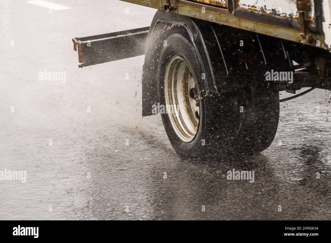 carrozza bianca corta che si muove su una strada bagnata con spruzzi durante una giornata piovosa Foto Stock