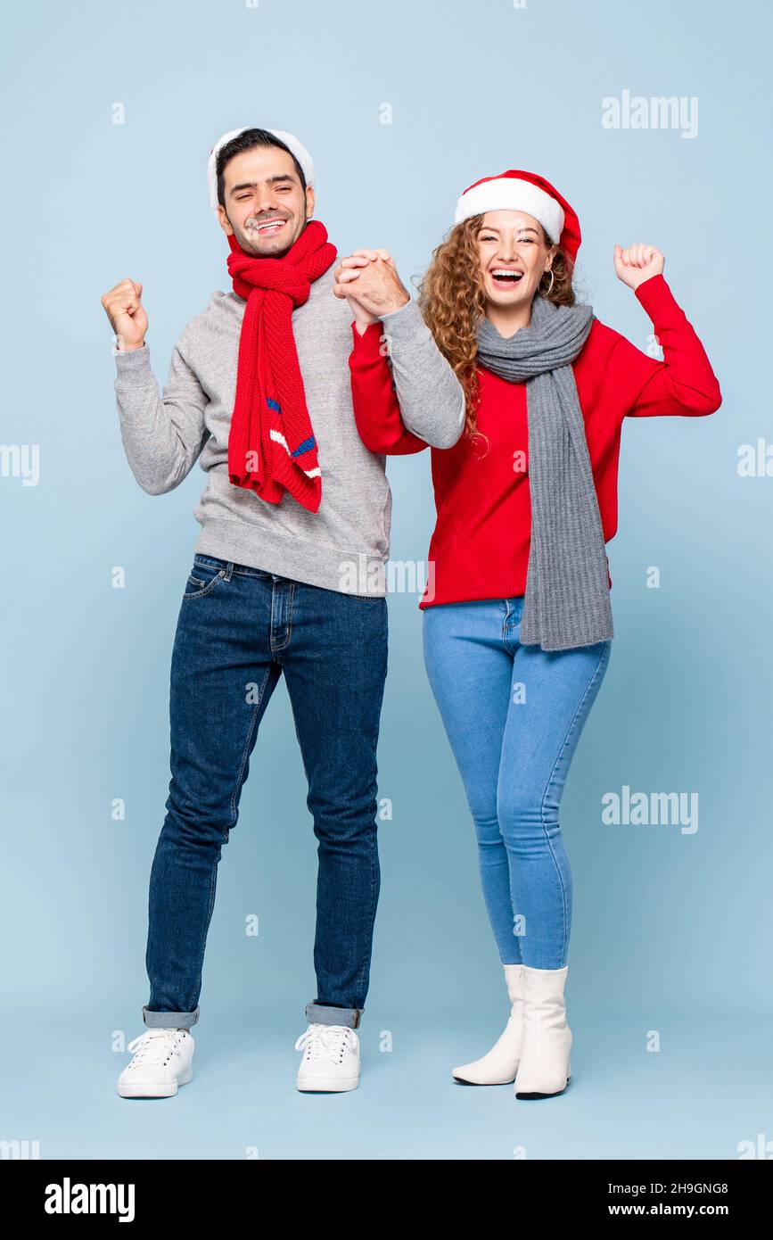 Ritratto a tutta lunghezza di coppia caucasica indossando abiti di Natale tenendo le mani in blu chiaro isolato studio sfondo Foto Stock