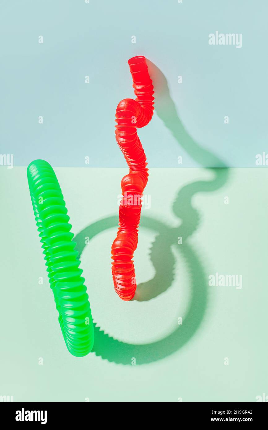 Il tubo pop curvo è appoggiato contro la parete. Vita morta moderna con giocattolo antistress. Foto Stock