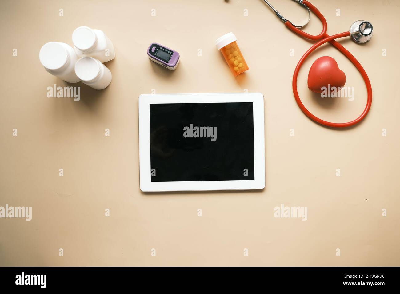 tablet digitale, stetoscopio e contenitore per pillole su tavolo Foto Stock