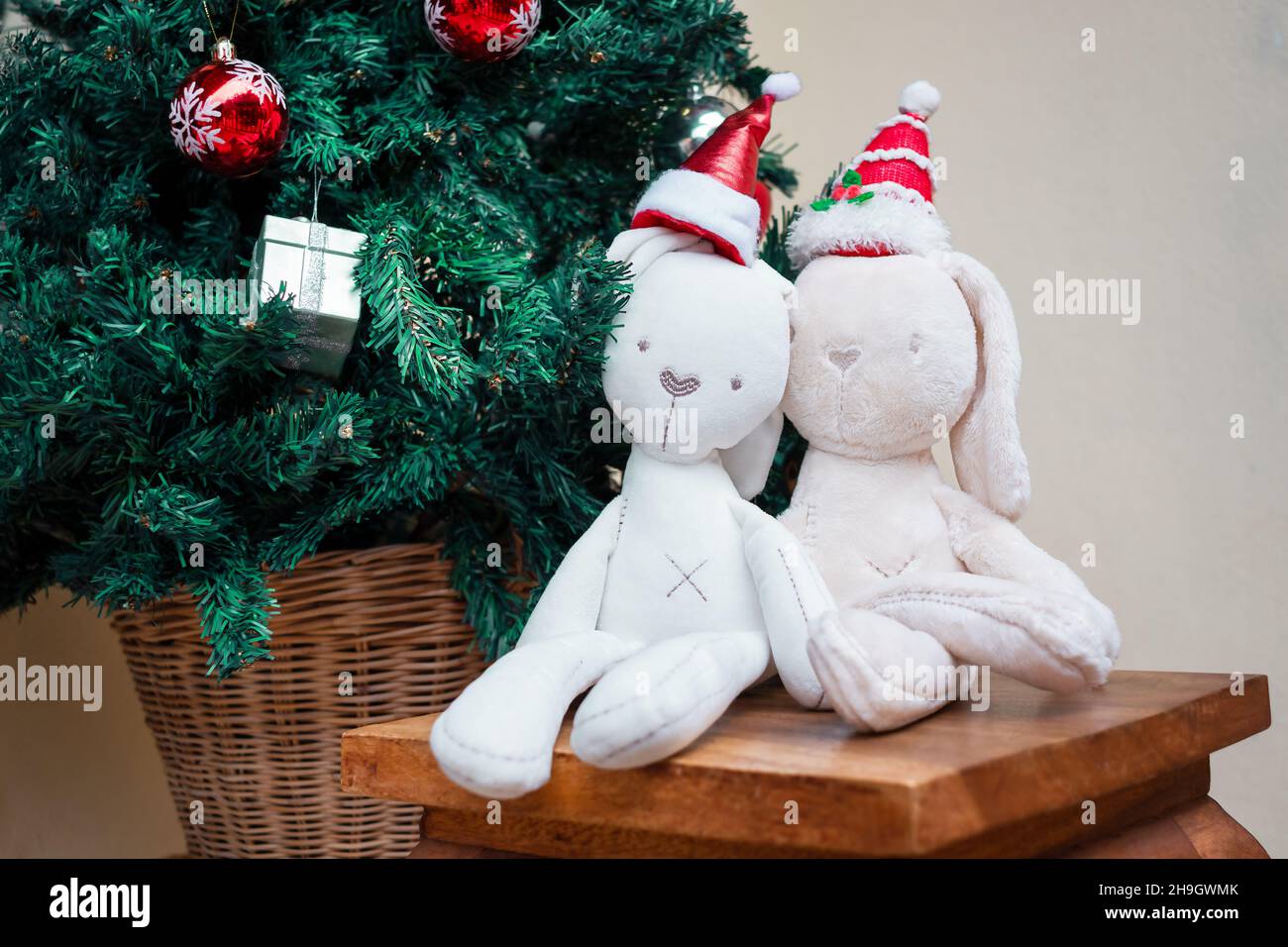 due coniglietti giocattolo nel cappellino di natale vicino all'albero di natale Foto Stock