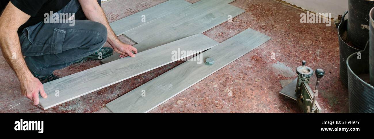 Mattonella che mette le mattonelle per installare un pavimento Foto Stock
