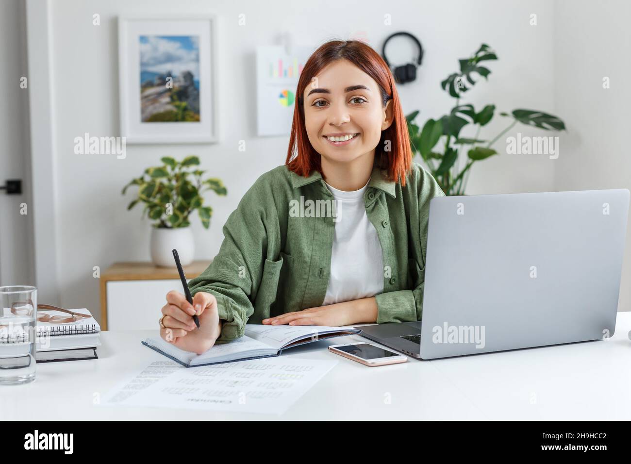 Donna che lavora da remoto a casa con un computer portatile. Giovane donna d'affari che pianifica il suo tempo. Concetto di business online, freelance, home Office e tel Foto Stock