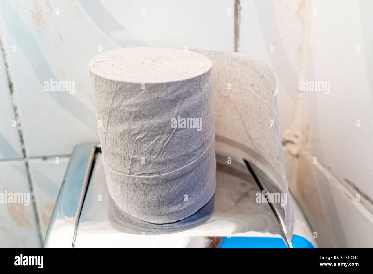 Rotolo di carta igienica poco costosa su un supporto di metallo in un bagno pubblico wc Foto Stock