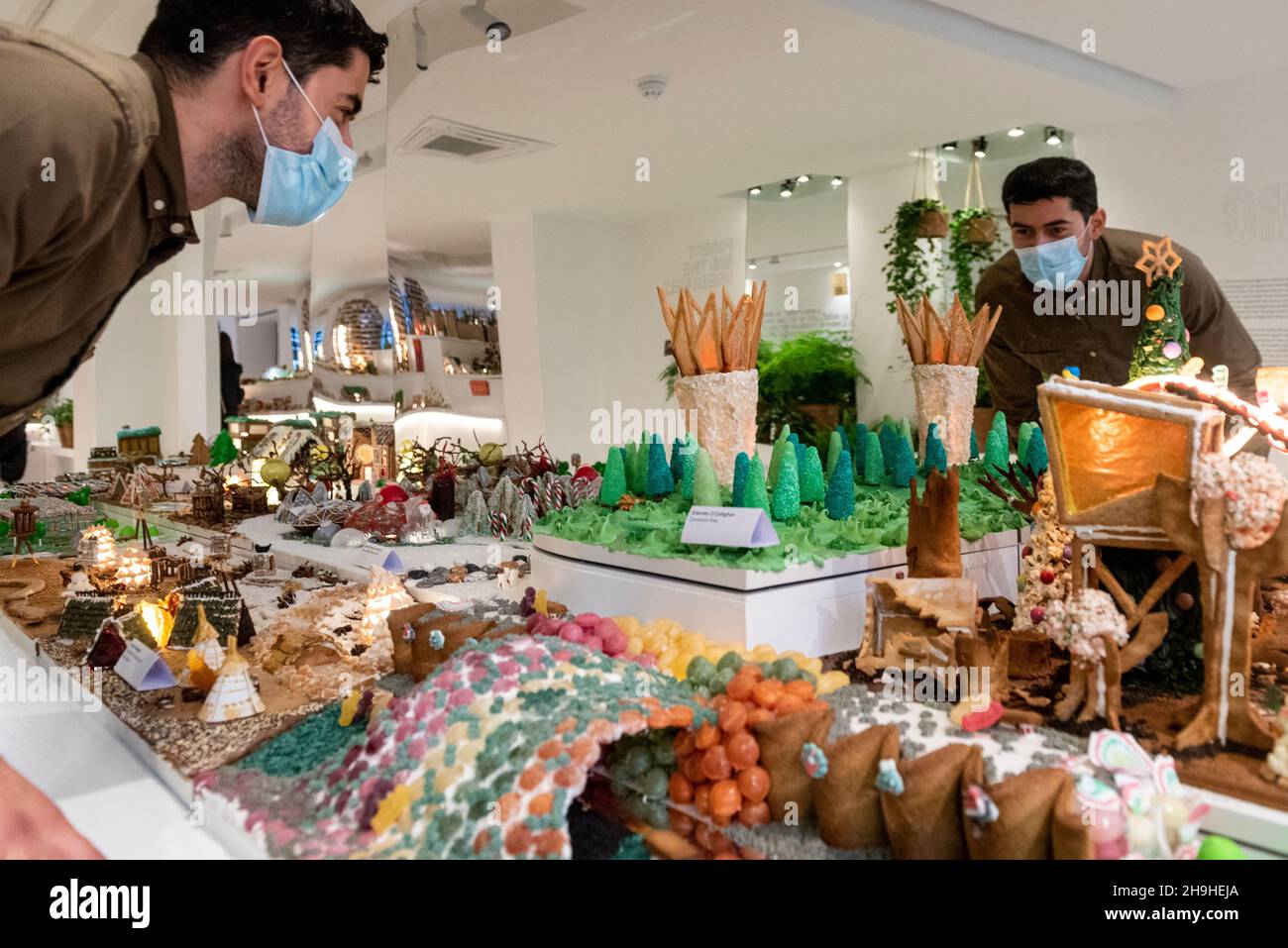 Londra, Regno Unito. 7 dicembre 2021. Un membro dello staff vede parte della città di Gingerbread, una mostra annuale in cui architetti, designer e ingegneri creano un'intera città fatta di pan di zenzero per collegare il pubblico all'architettura attraverso un'esposizione innovativa progettata per la stagione festiva. Fondata dal Museo dell’architettura, la mostra di quest’anno si concentra sul concetto di “riavvilimento della città” e può essere visitata in Motcomb Street, Belgravia fino al 9 gennaio 2022. Credit: Stephen Chung / Alamy Live News Foto Stock