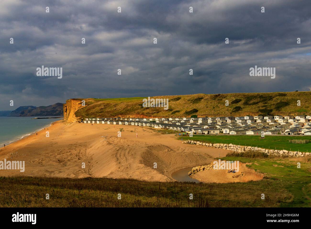 Un pozzo di luce solare autunnale illumina l'instabile East Cliff di arenaria e un enorme sito statico di casa mobile sulla Jurassic Coast a Burton Bradstock Foto Stock